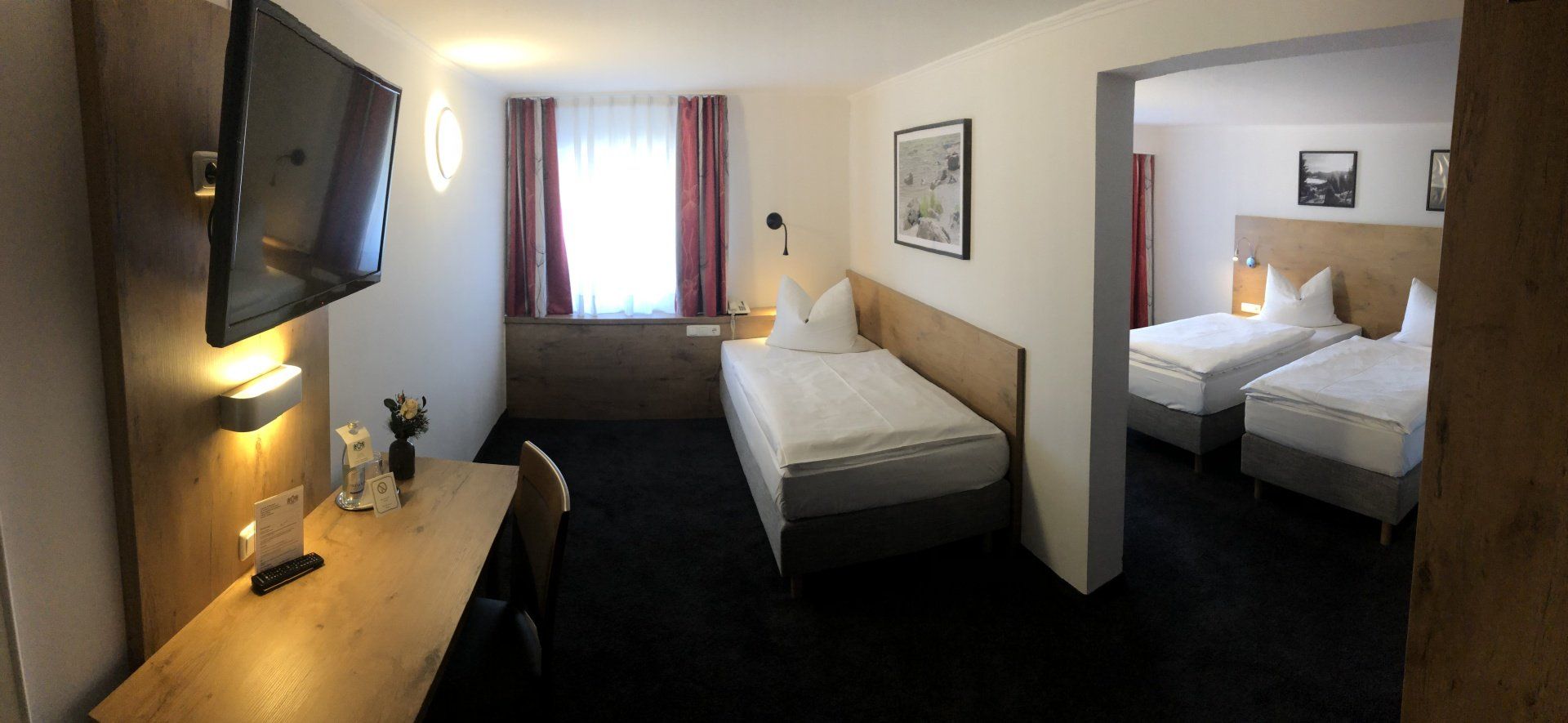 Una camera d'albergo con due letti, una scrivania e una TV a schermo piatto.