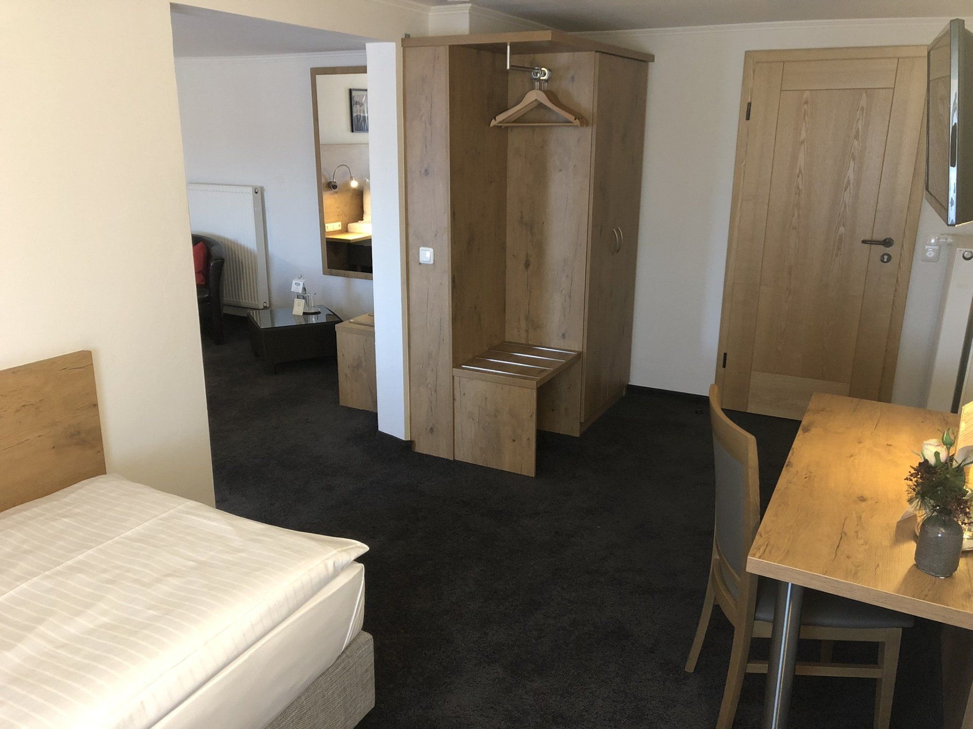 Una camera d'albergo con un letto singolo, tavolo e sedie.