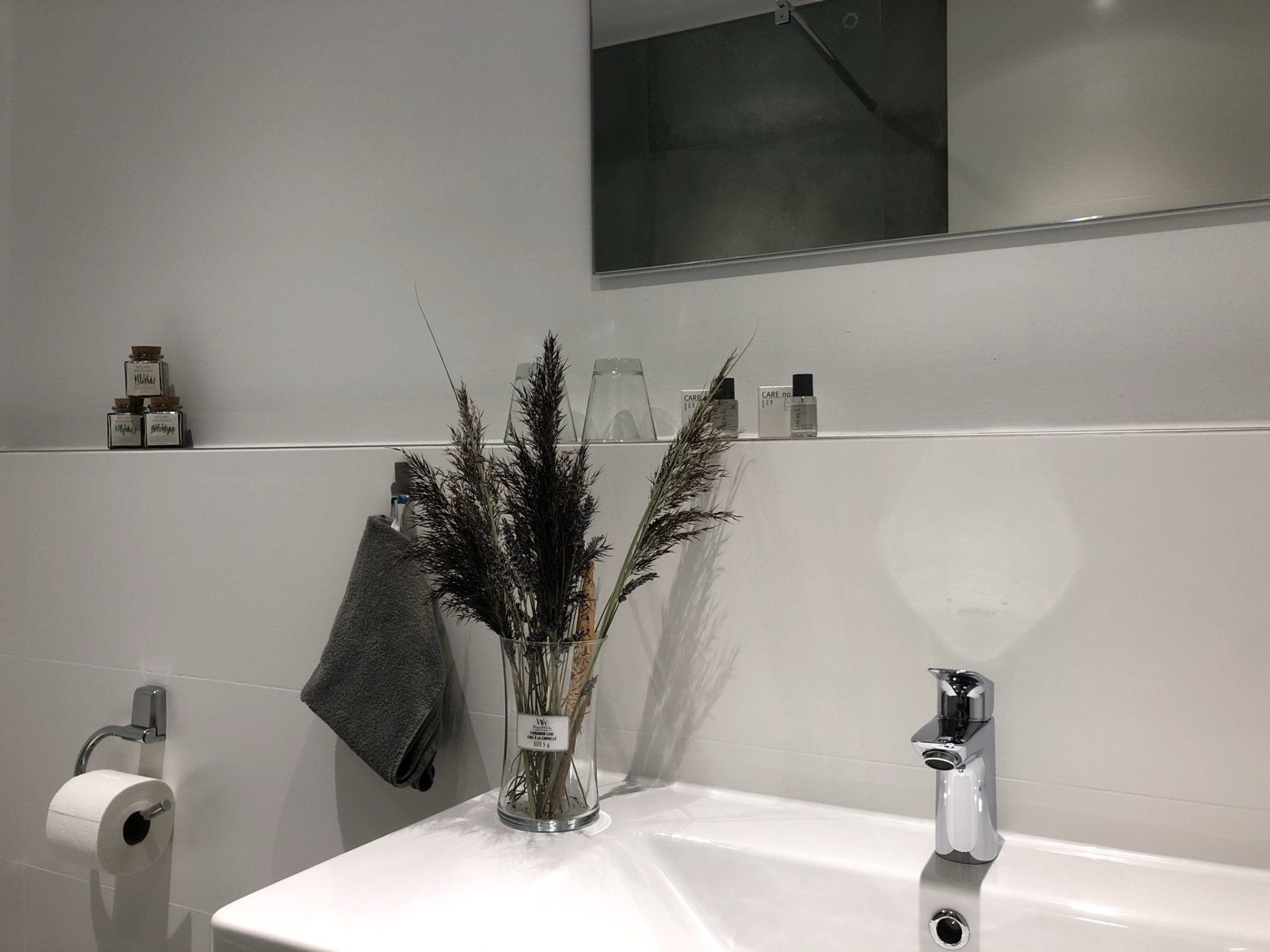 Un lavandino del bagno con un vaso di fiori sopra.