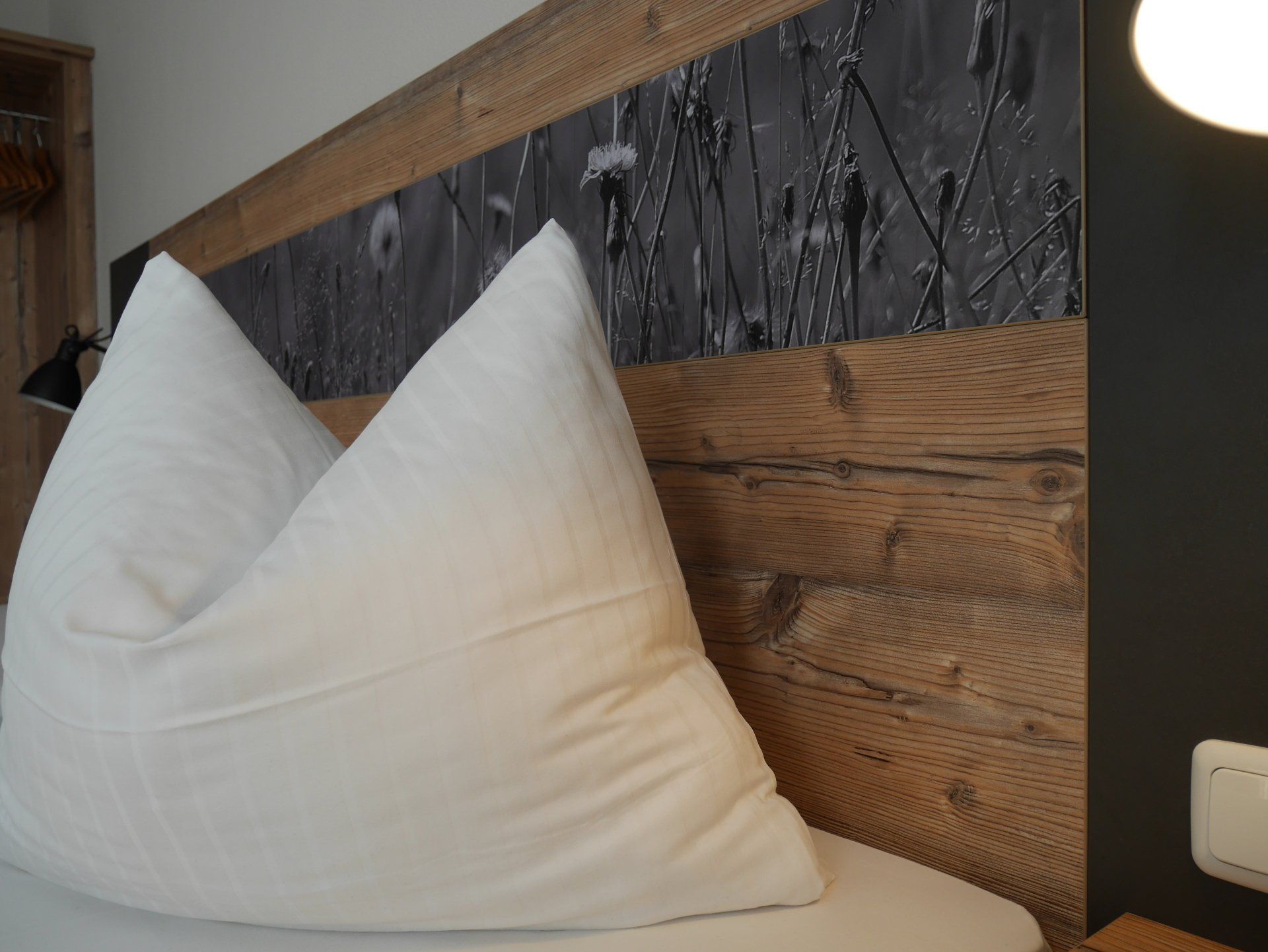 Un letto con un cuscino bianco e una testiera di legno