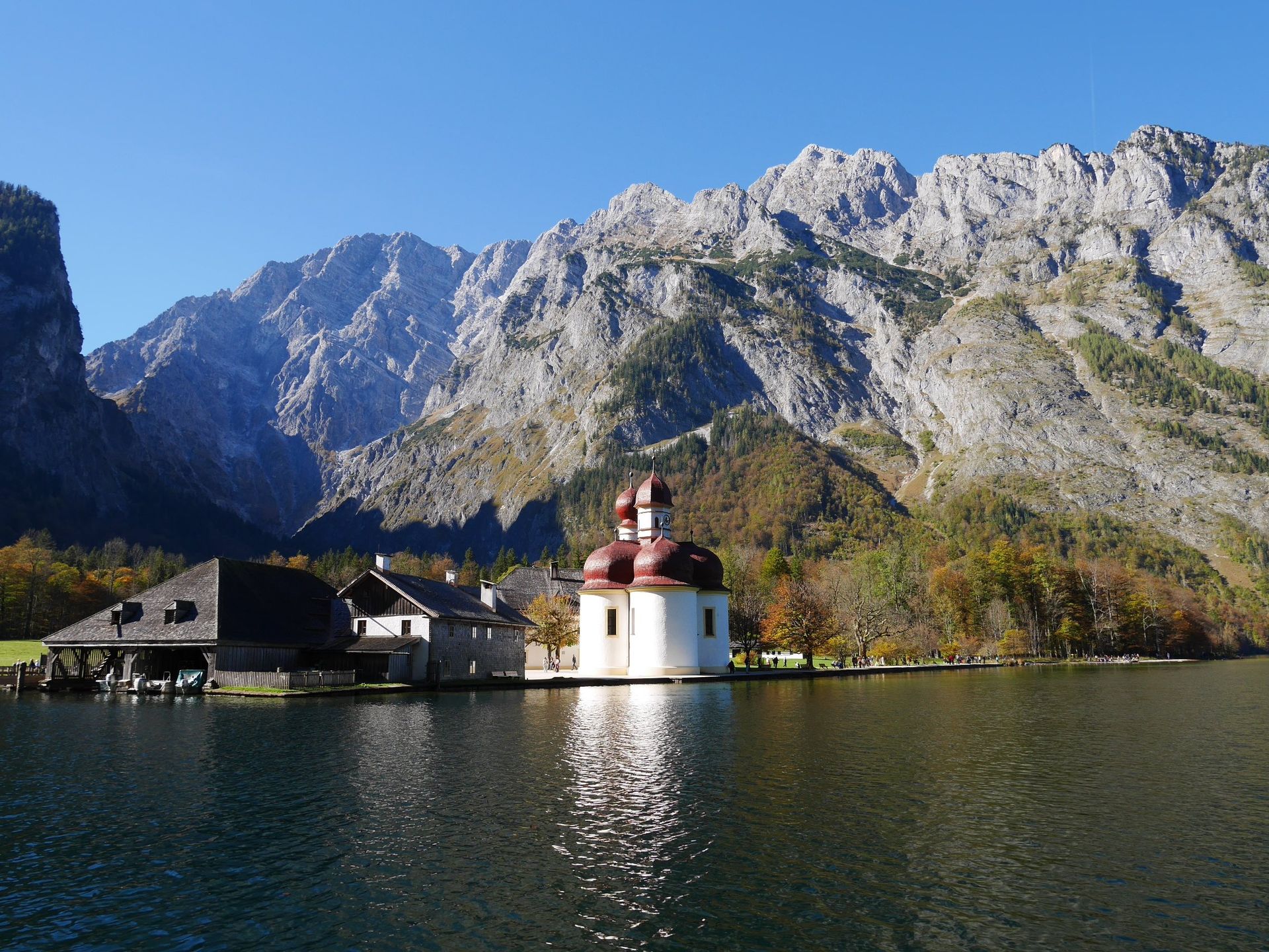 A small island in the middle of a lake with mountains in the background