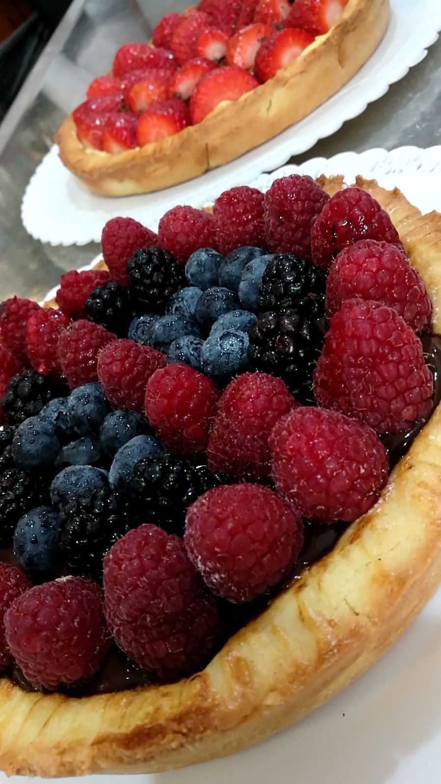 Crostate di frutti di bosco: lamponi, mirtilli, more e fragole disposti su croste cotte al forno, su piatti bianchi.