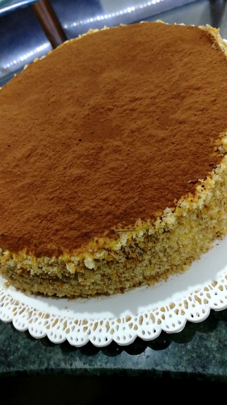 Torta con spolverata di cacao in polvere su un centrino bianco.