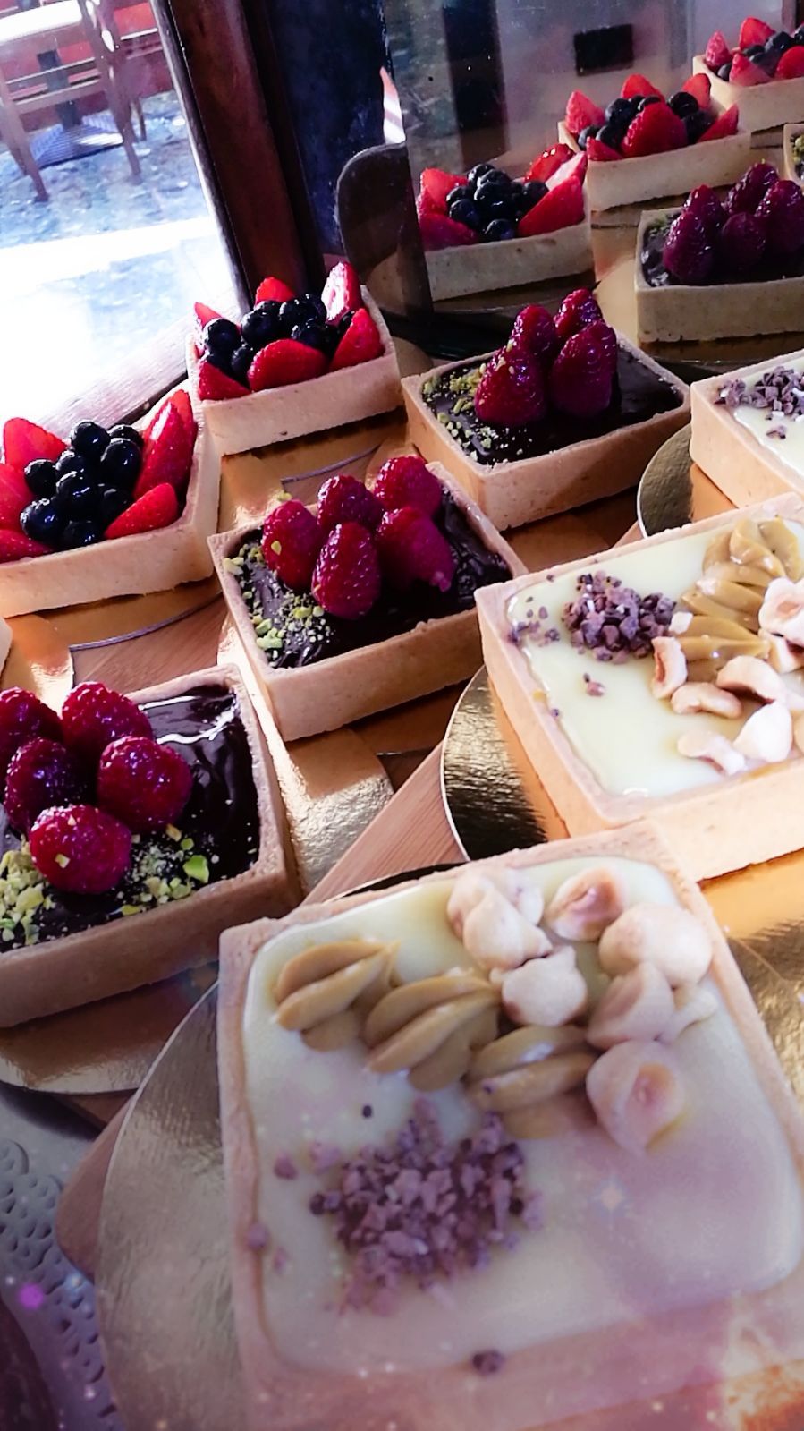 Crostate di frutta quadrate con lamponi, mirtilli, fragole e noci su un vassoio dorato.