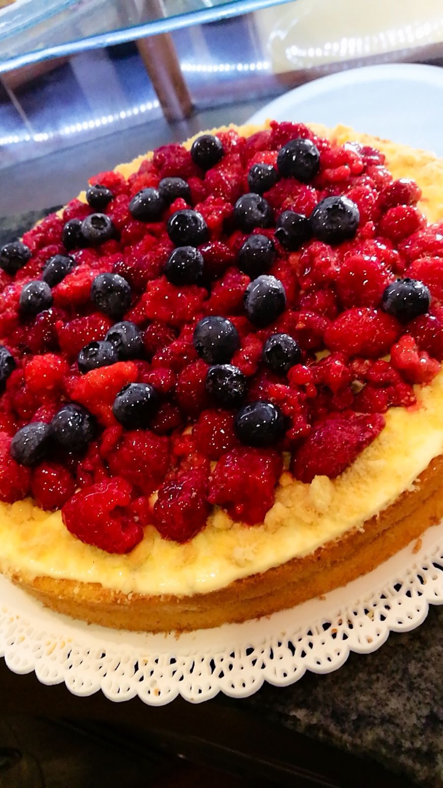 Crostata di frutti di bosco, lamponi e mirtilli su una crosta dorata su un centrino bianco.