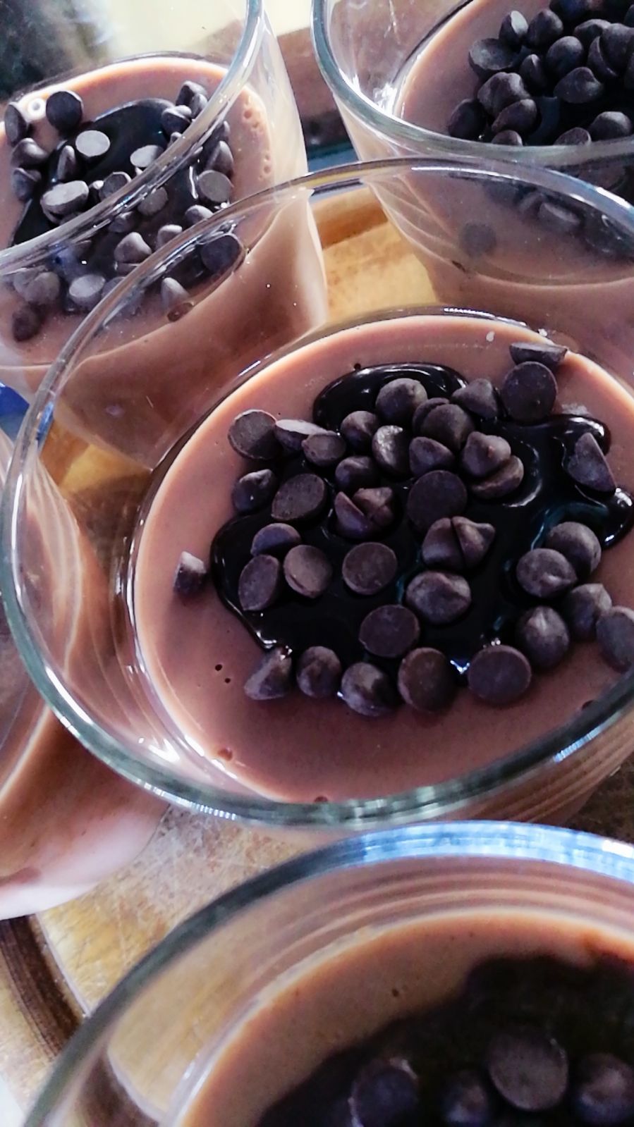 Dessert al budino al cioccolato ricoperti di gocce di cioccolato, serviti in ciotole di vetro.