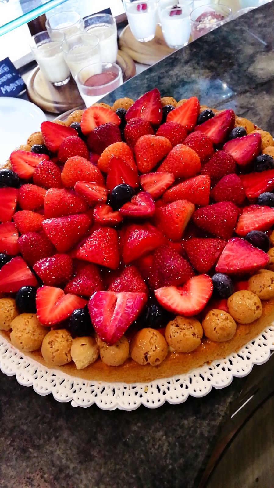 Crostata di fragole con bordo di biscotto, guarnita con fragole e mirtilli freschi.