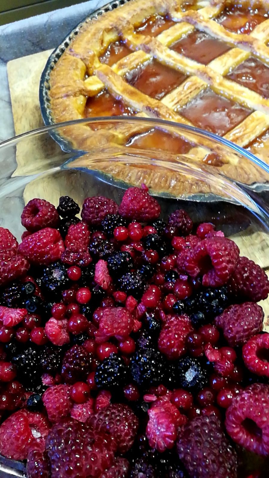 Torta ai frutti di bosco e ciotola di lamponi freschi, more e ribes rossi.