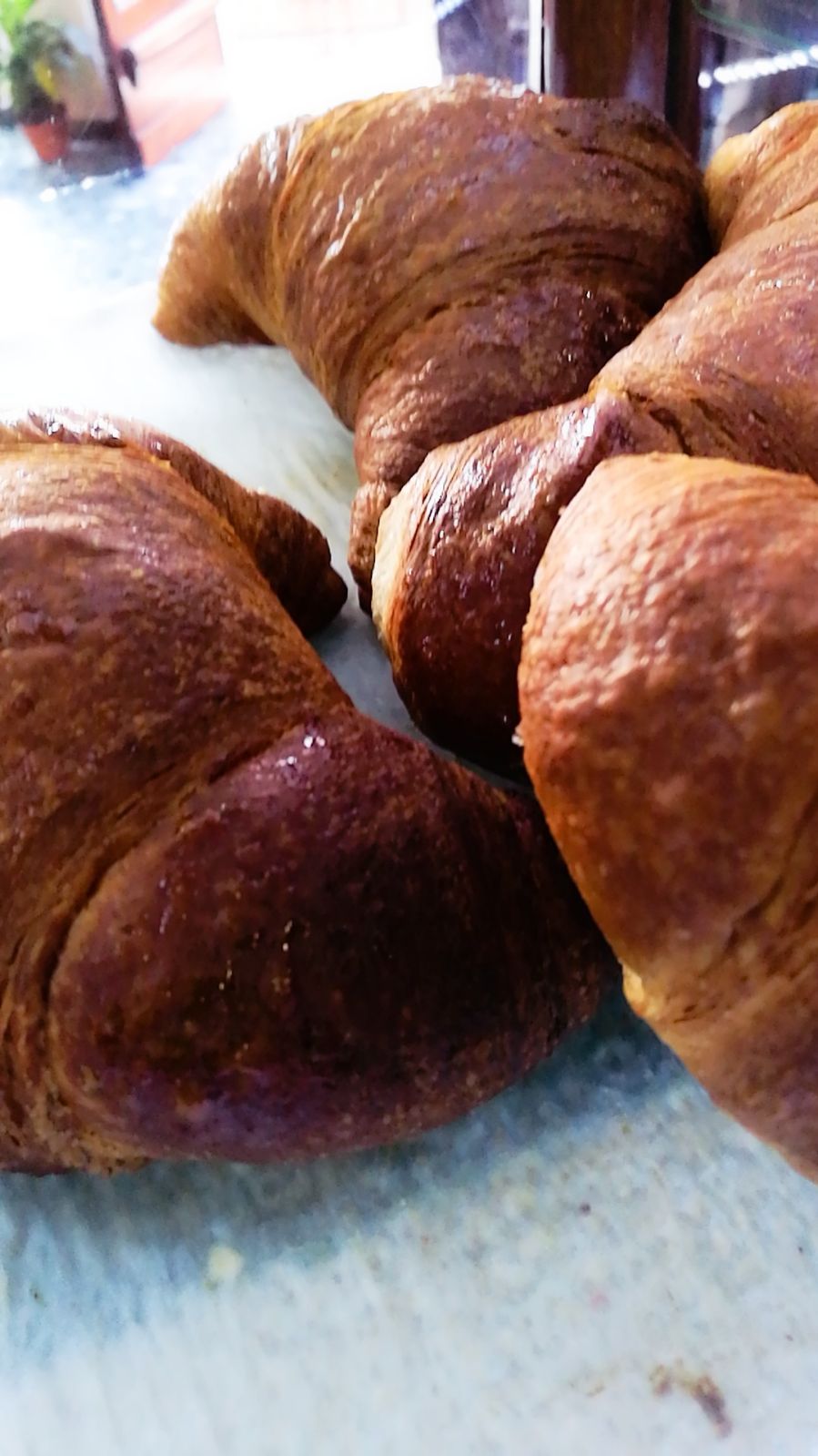 Primo piano di croissant dorati su una superficie bianca e blu.