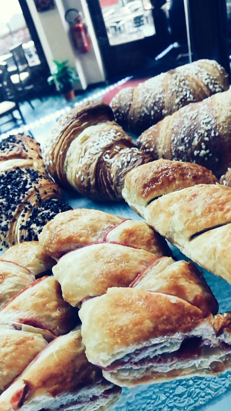 Assortimento di dolciumi, tra cui croissant e pasticcini ripieni, esposti in una panetteria.