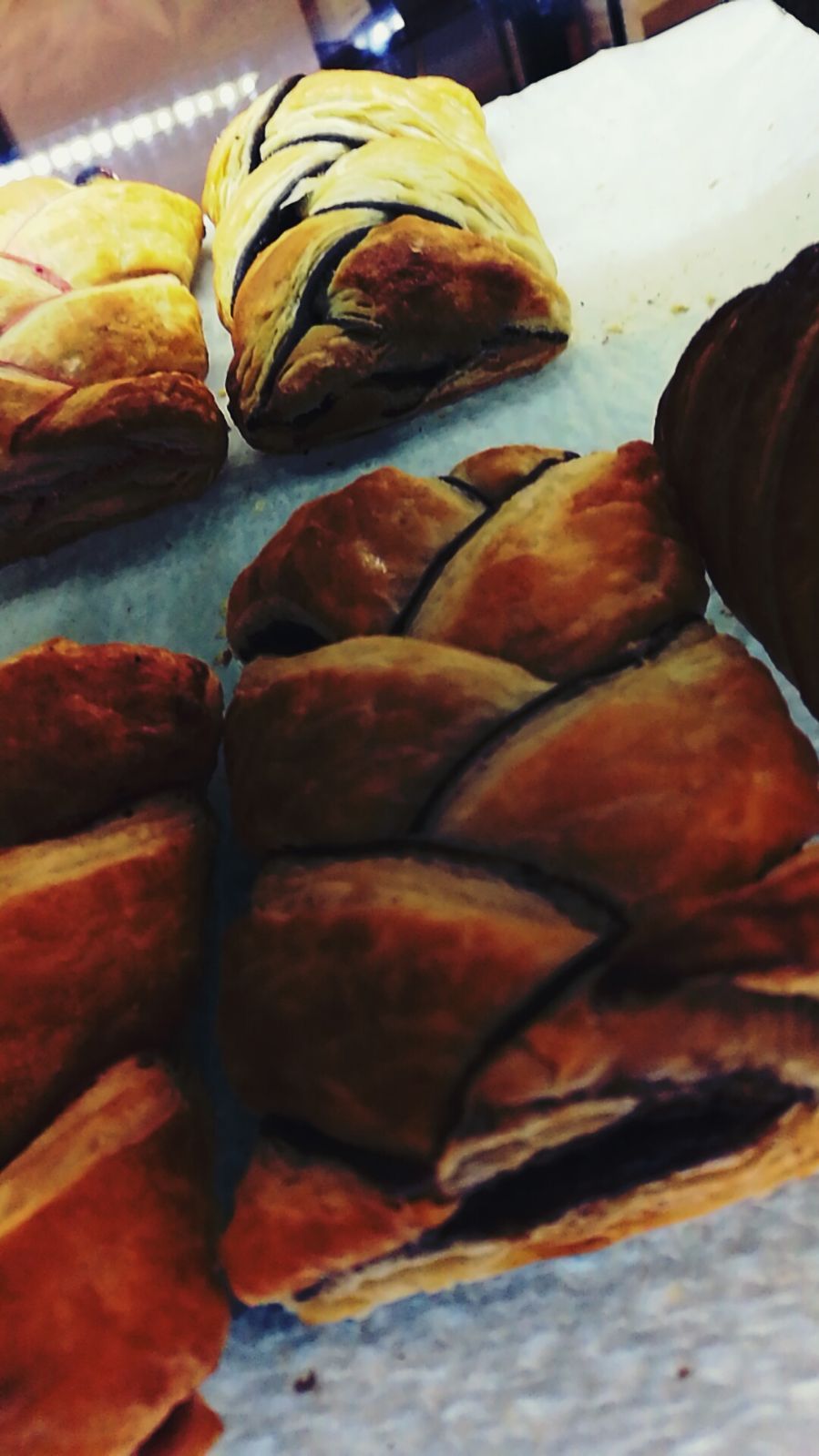 Pasticcini intrecciati con ripieno di cioccolato, esposti su un bancone.