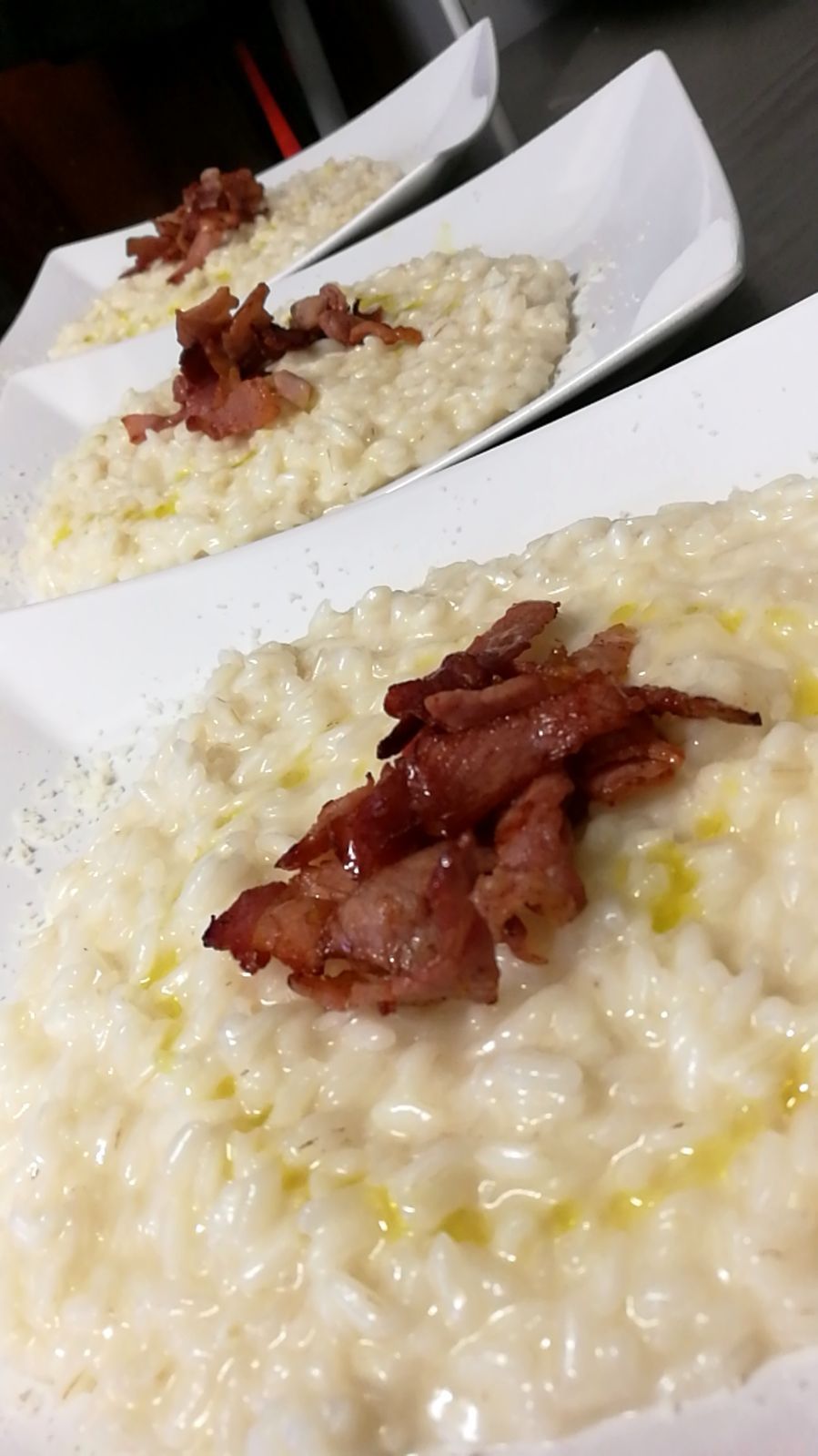 Tre piatti di risotto cremoso con pancetta croccante.