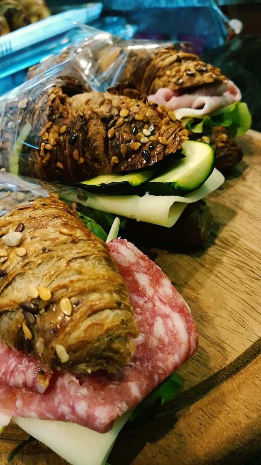 Tre panini con ripieni assortiti su un tagliere di legno.