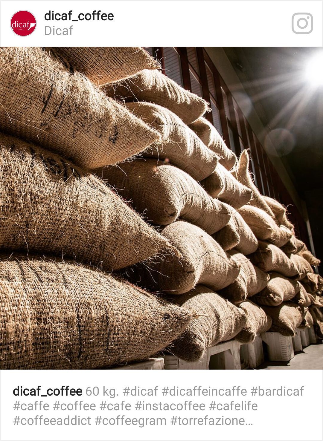 Sacchi di chicchi di caffè impilati in alto, con una luce intensa che brilla sullo sfondo.