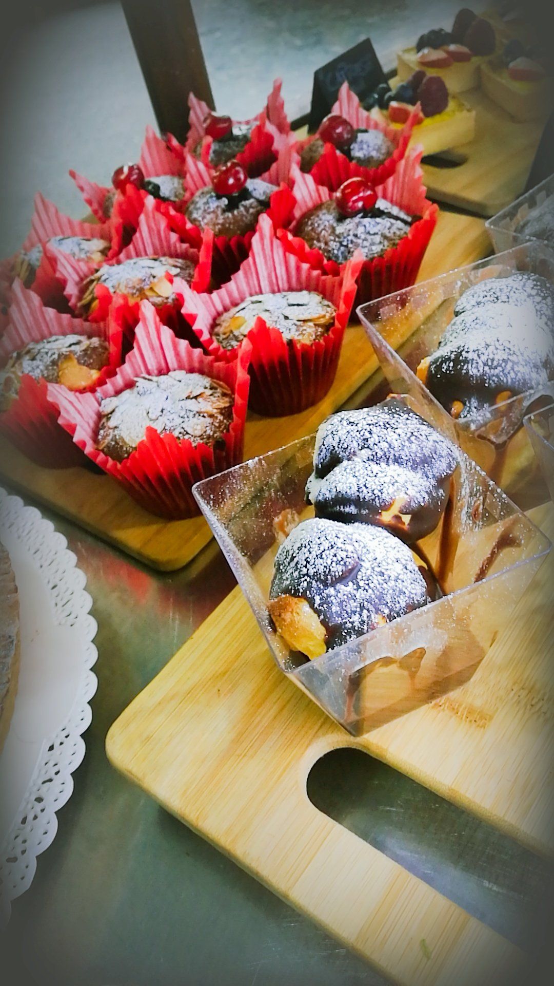 Muffin in involucri rossi e pasta sfoglia con zucchero a velo, esposti su tavole di legno.