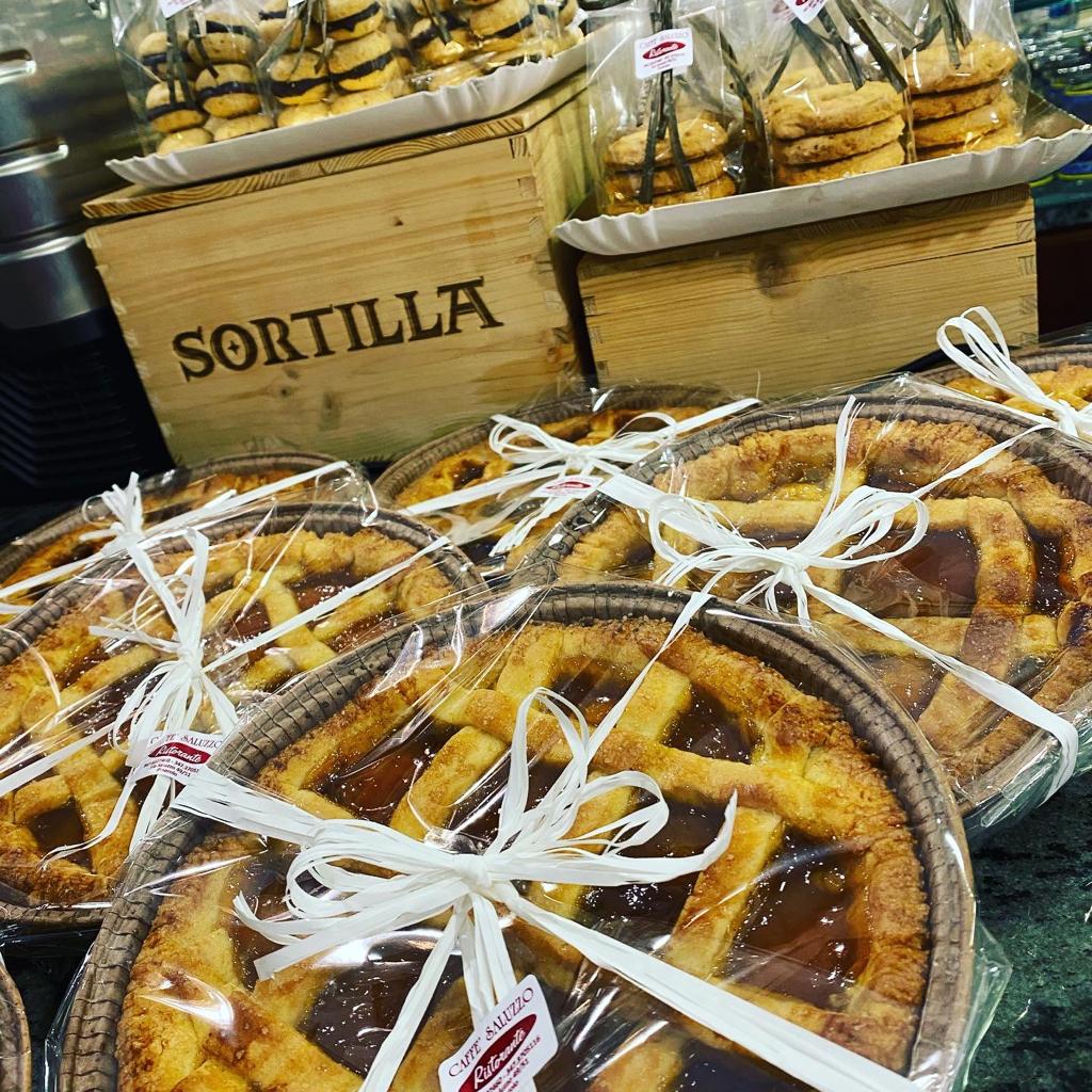 Pasticcini esposti, tra cui crostate e biscotti confezionati, con una scatola di legno con l'etichetta