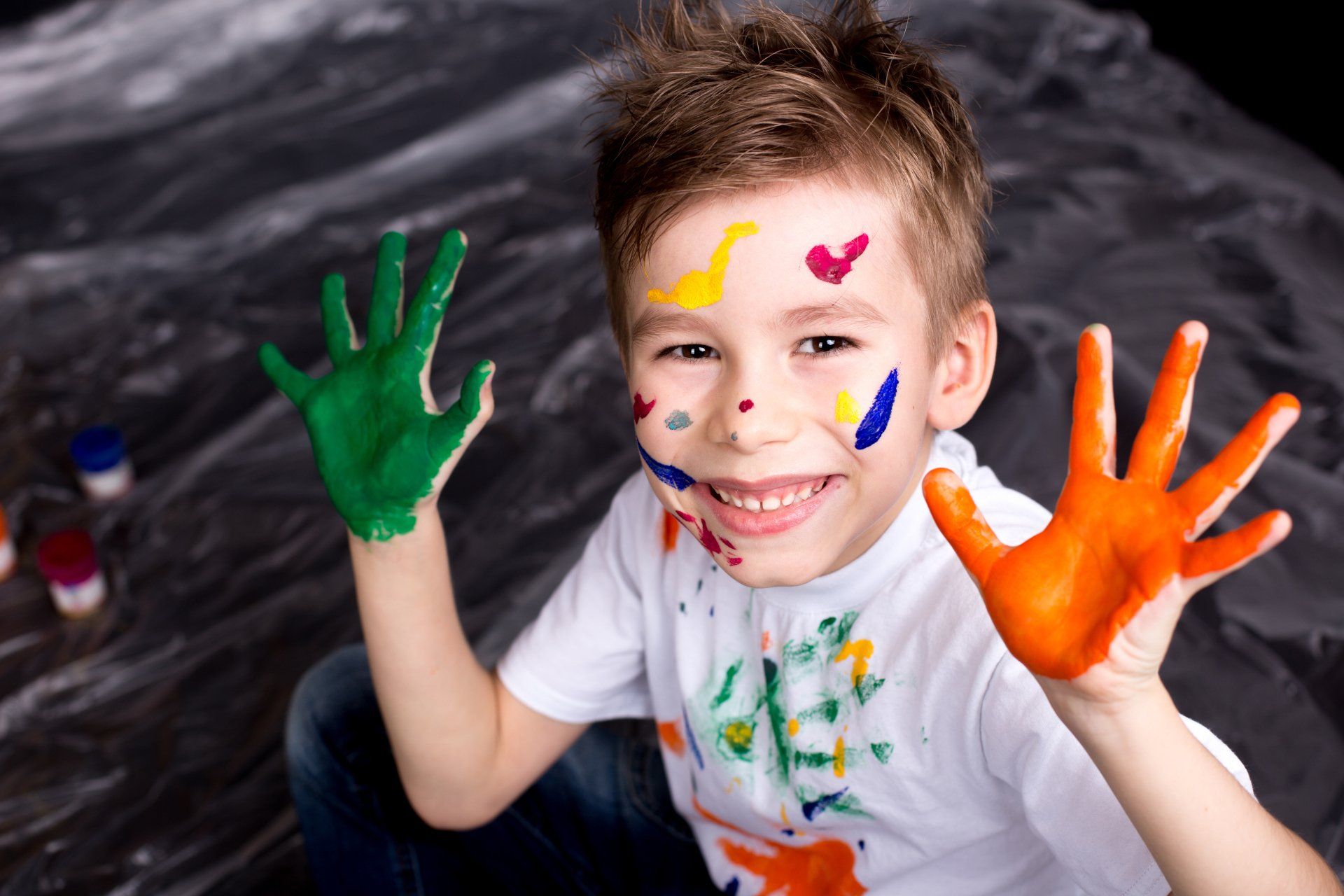 A young boy with paint on his face and hands