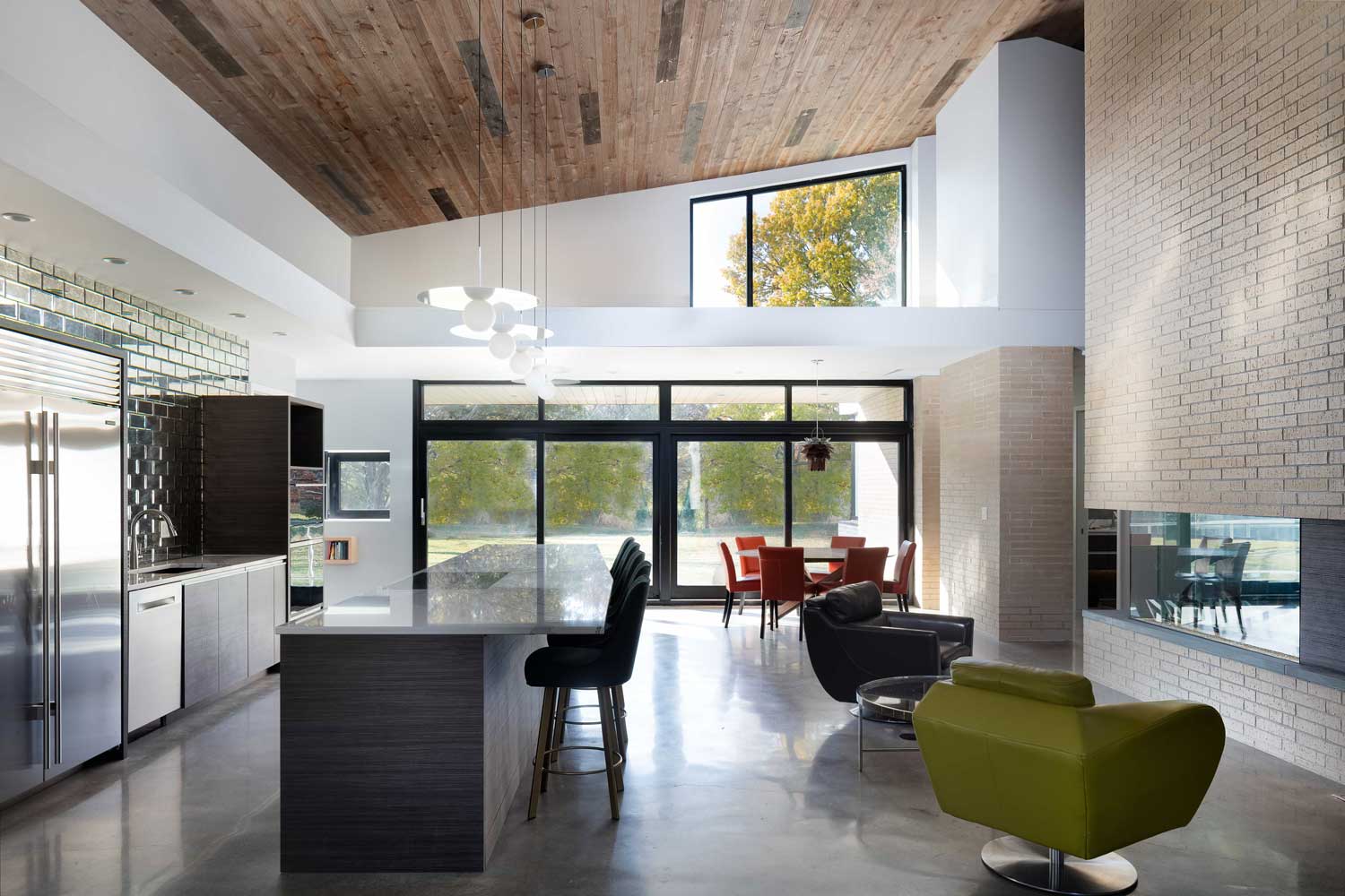 Modern kitchen and dining area with natural wood vaulted ceiling and large windows