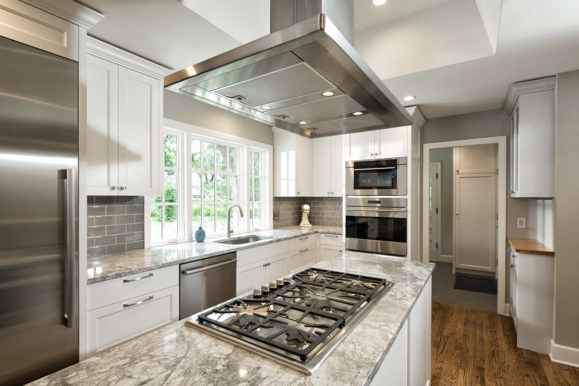 Large kitchen island with gas stovetop and stainless steel hood