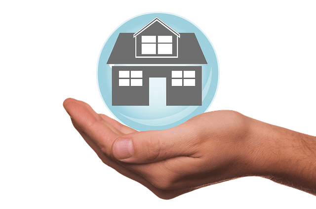 Hand holding a house icon inside a blue circle.