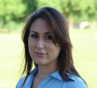 A woman in a blue shirt is standing in a field.