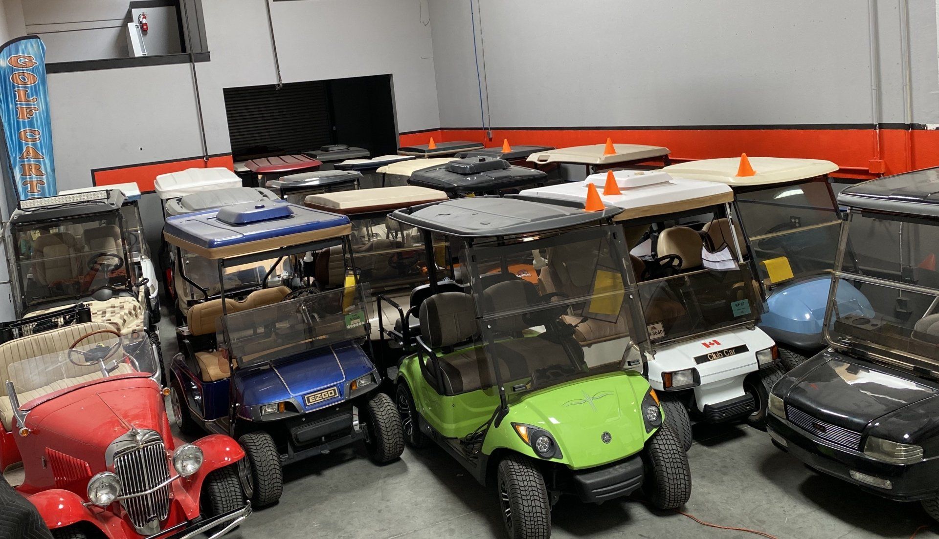 A bunch of golf carts are parked in a garage.