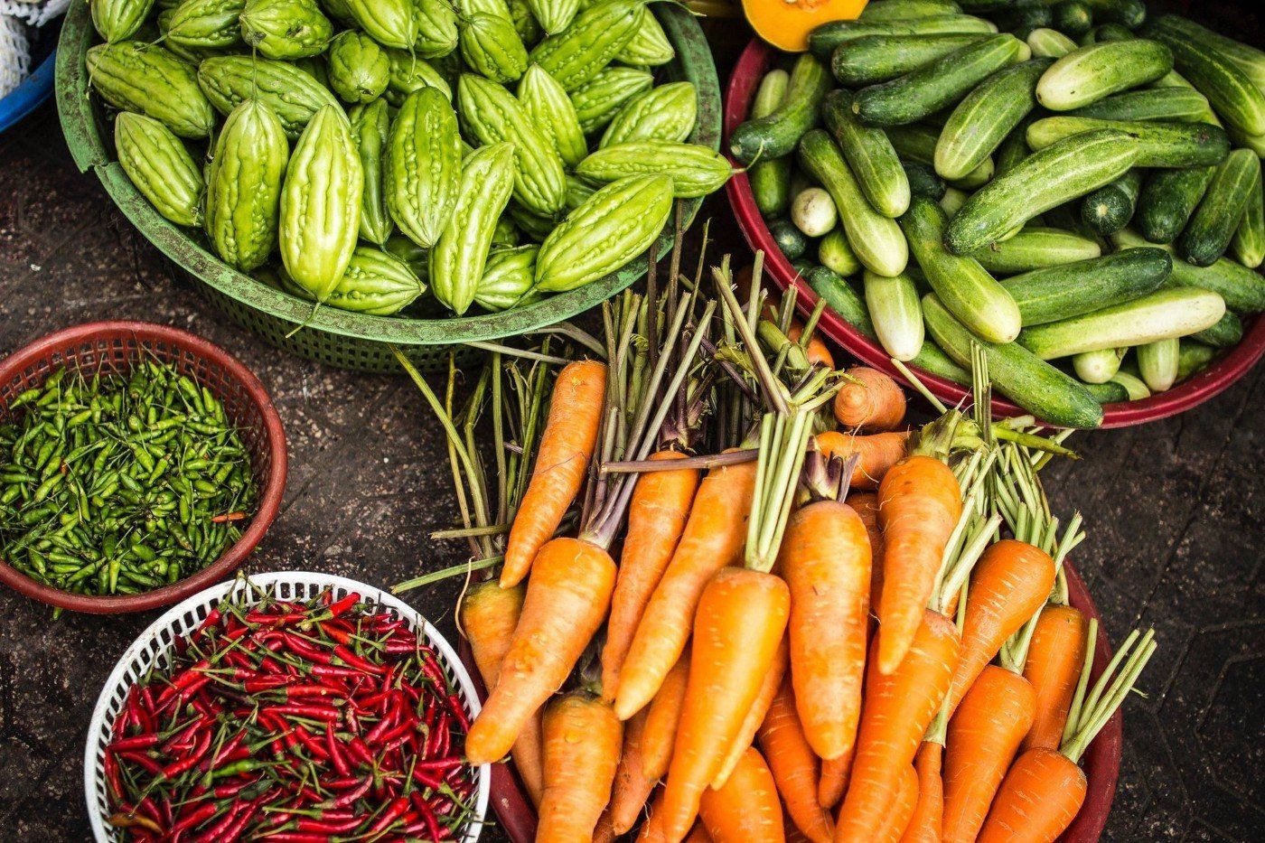 There are many different types of vegetables in bowls on the table.