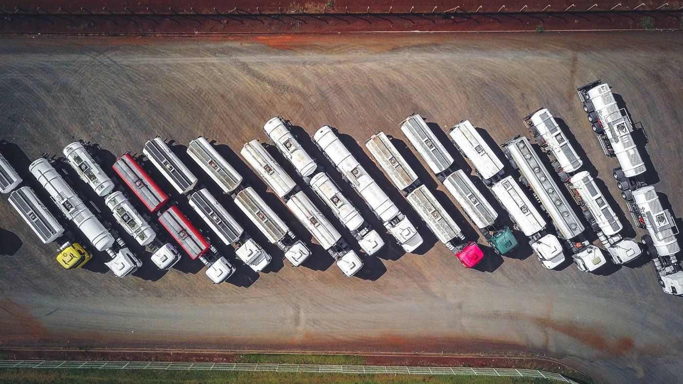 An aerial view of a row of semi trucks parked in a parking lot.