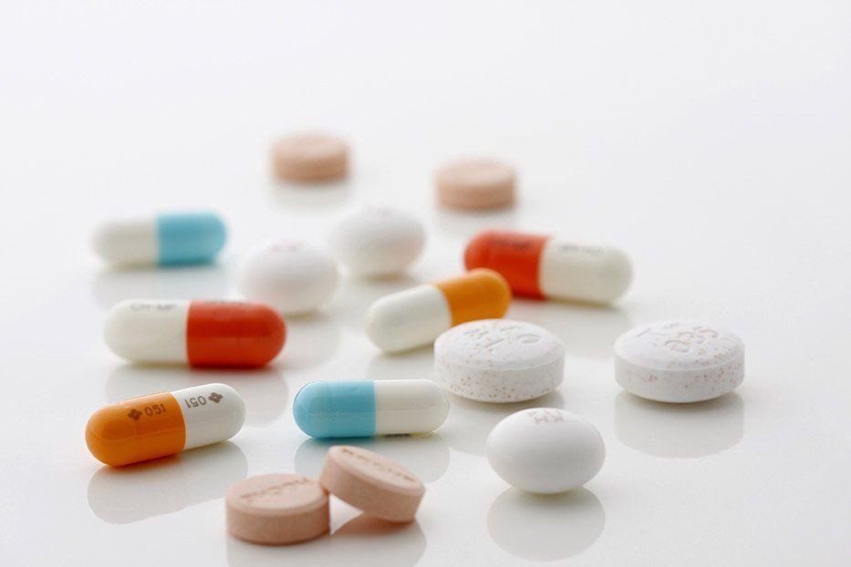 A pile of pills and capsules on a white surface.