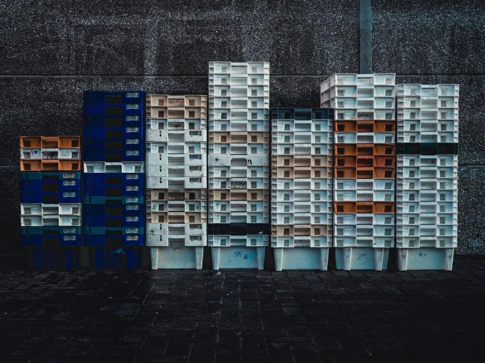 A row of plastic crates stacked on top of each other on the ground.