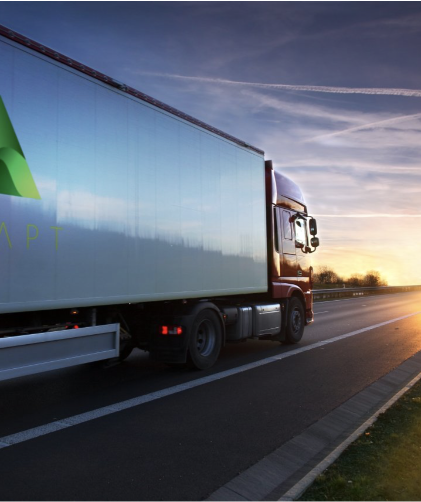 A semi truck is driving down a highway at sunset