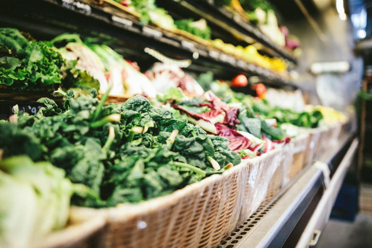 A row of baskets filled with vegetables in a grocery store.