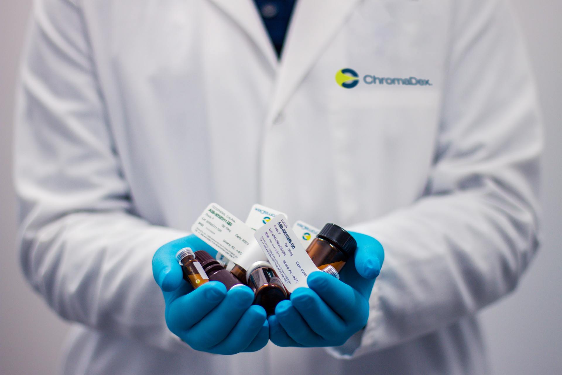 A doctor wearing blue gloves is holding a bunch of pills