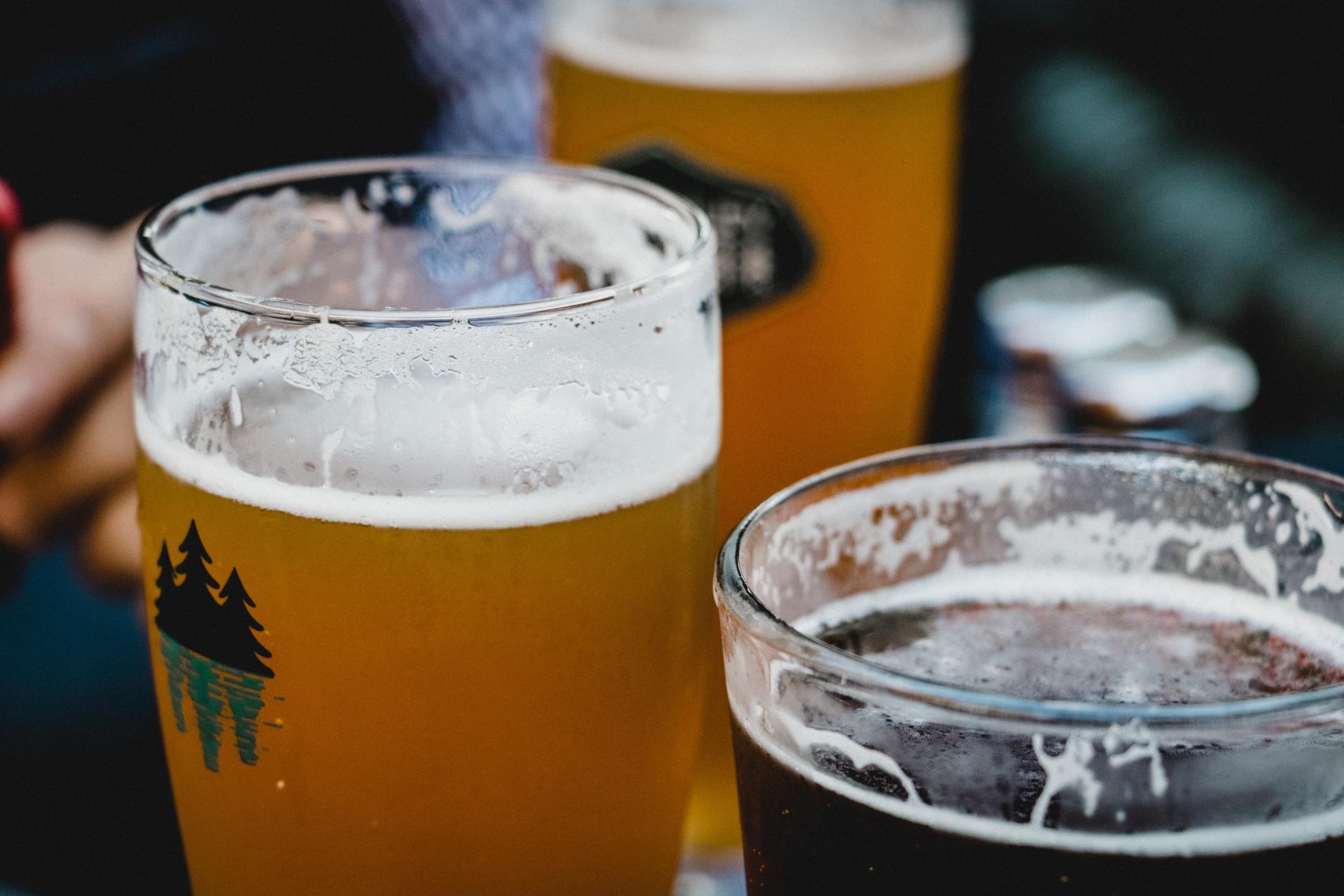 Three glasses of beer are sitting on a table.