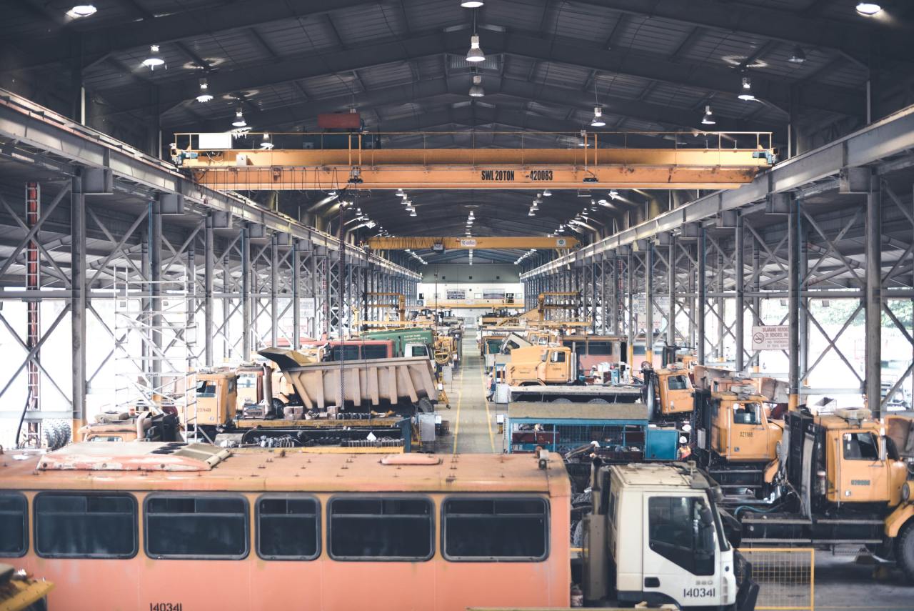 A large warehouse filled with lots of trucks and buses.