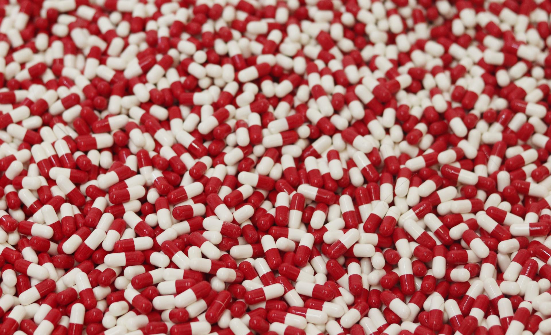 A pile of red and white pills on a table.