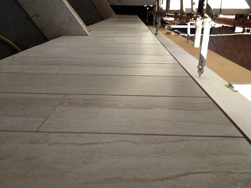 Primo piano di piastrelle rettangolari beige effetto legno installate in una mansarda in fase di ristrutturazione.