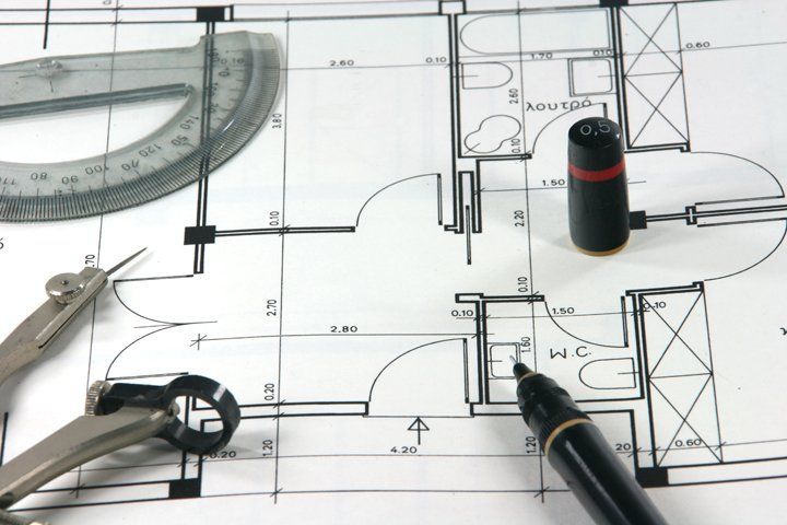 Una planimetria architettonica su carta con goniometro, compasso, penna tecnica e cappuccio.