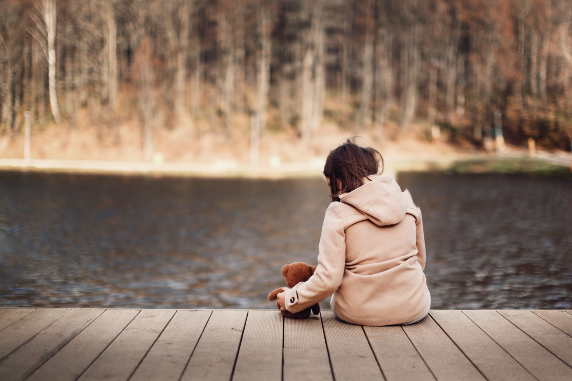teenage girl by a lake with teddy bear