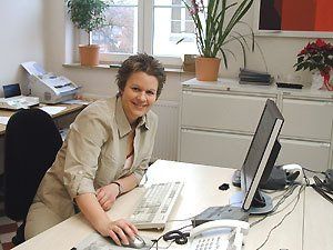 Eine Frau sitzt an einem Schreibtisch mit einem Computer und einem Telefon
