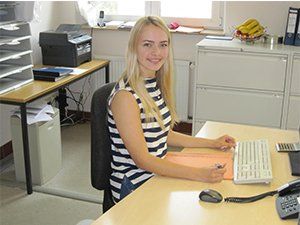 Eine Frau sitzt an einem Schreibtisch mit einer Tastatur und einem Telefon
