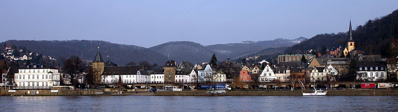 Eine Stadt an einem Gewässer mit Bergen im Hintergrund