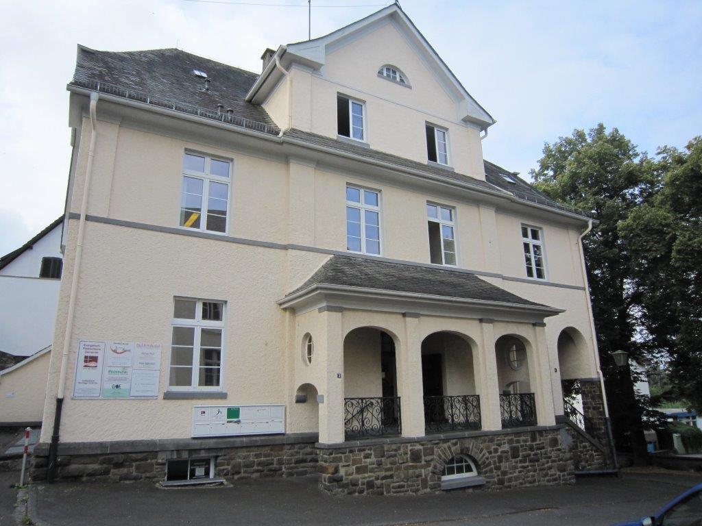 Ein großes weißes Gebäude mit einer Steinveranda und Bögen