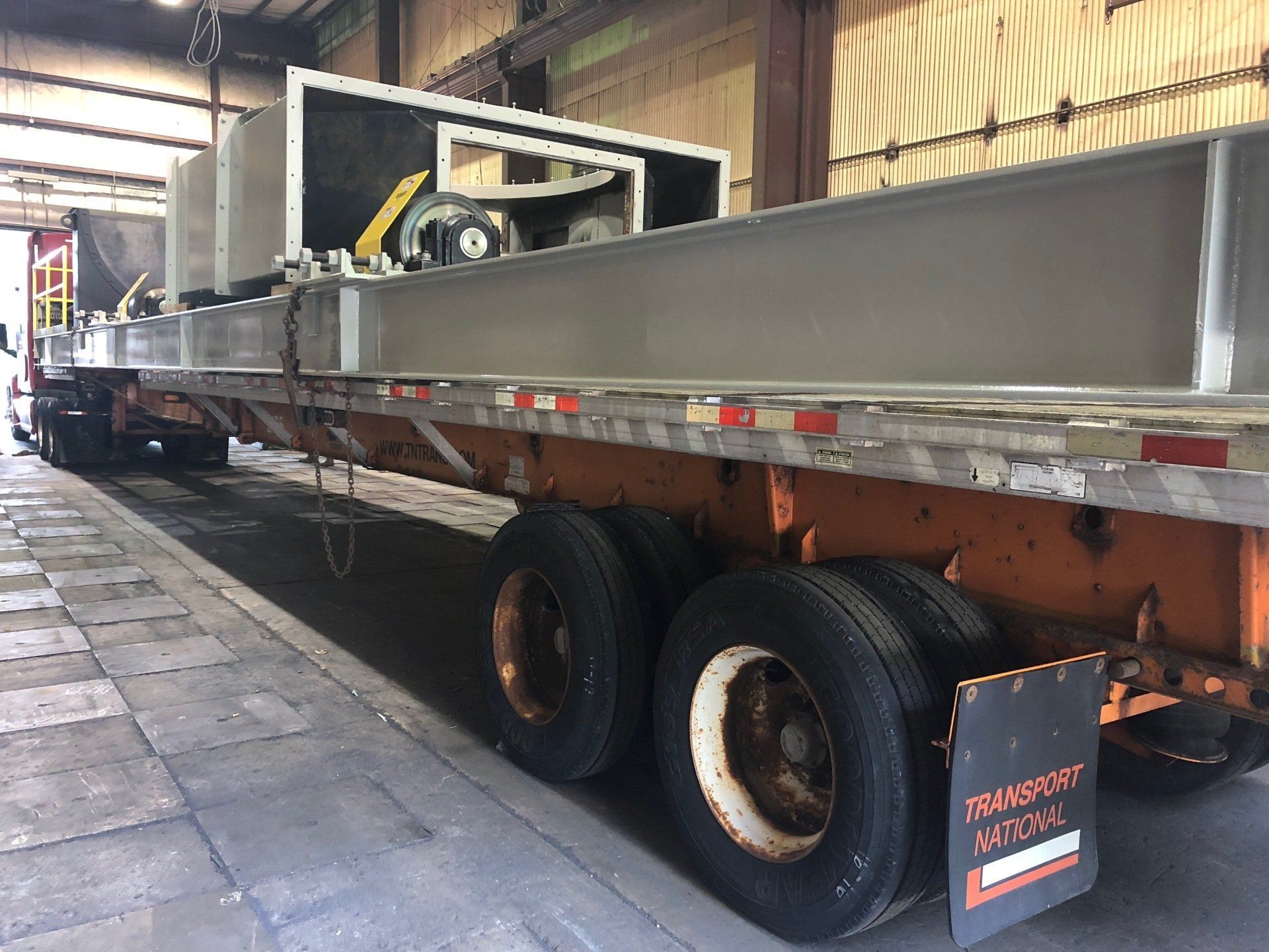 A semi truck is parked in a garage with a large metal structure on the back of it.