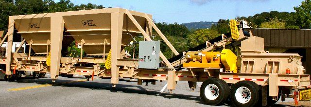 A truck is pulling a trailer with a machine on it.