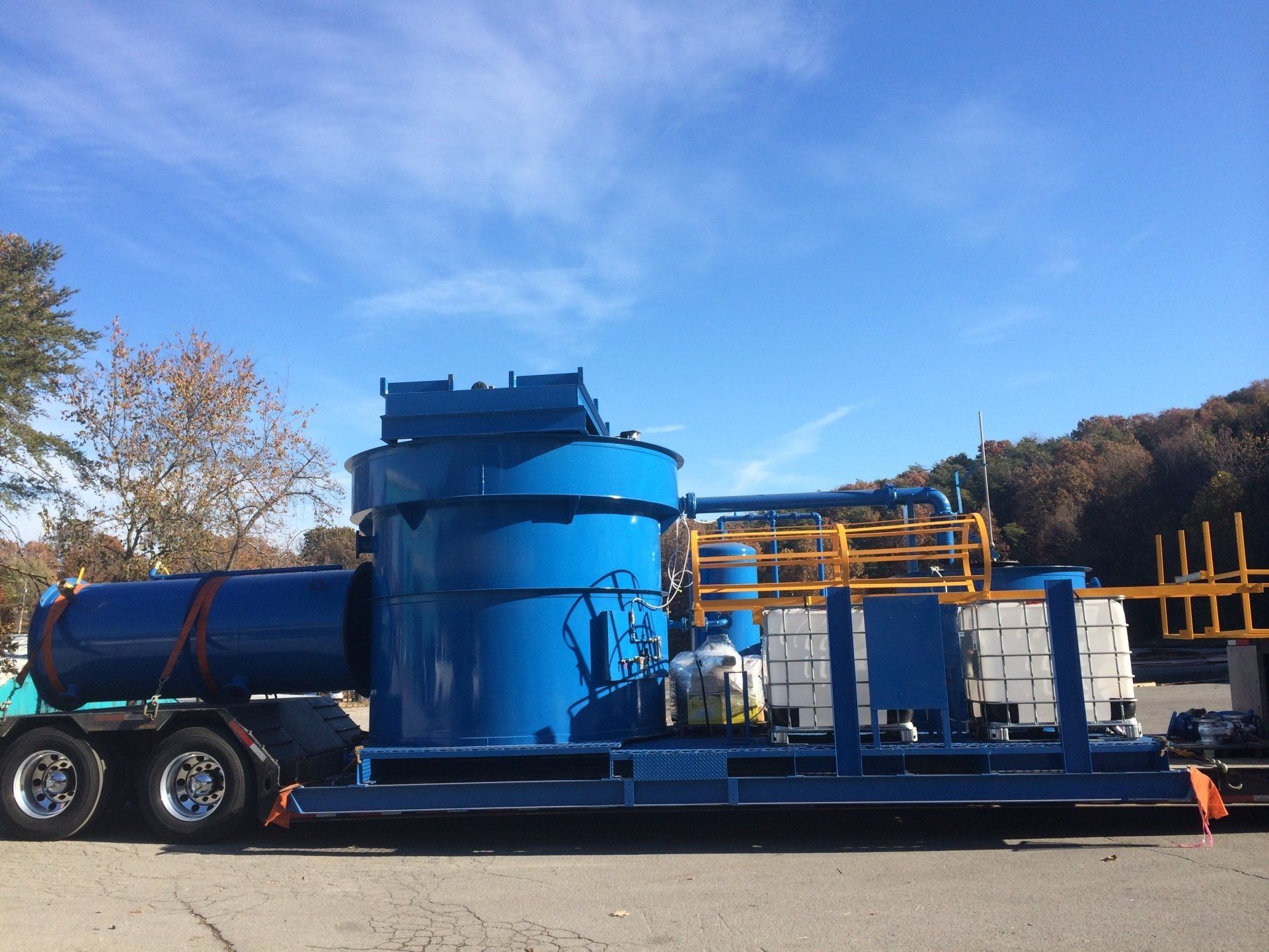 A large blue machine is on a trailer in a parking lot.