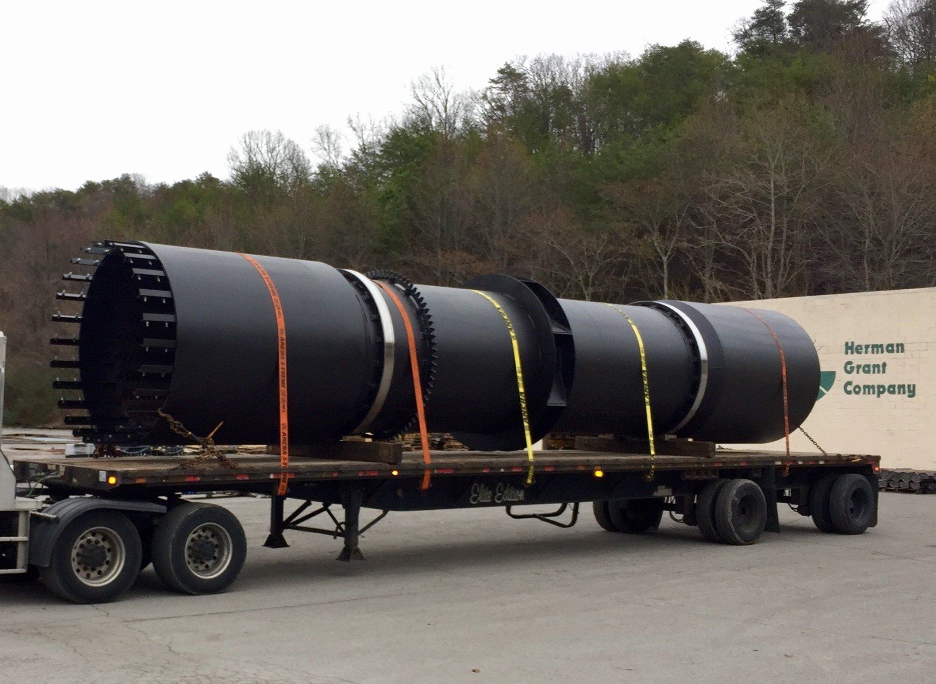 A large black pipe is being transported on a semi truck