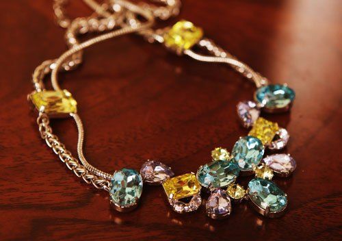 una collana con pietre di color azzurro viola e giallo