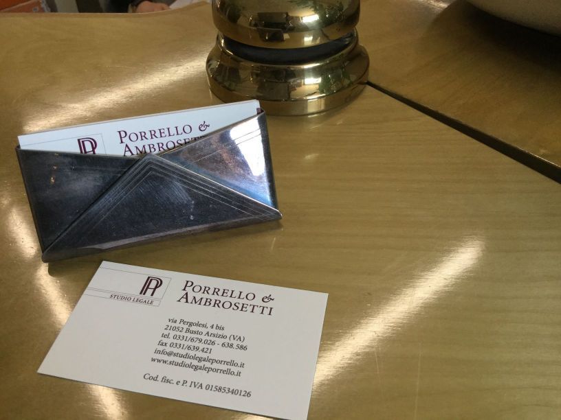Biglietto da visita e portabiglietti su superficie dorata, sul biglietto è scritto 