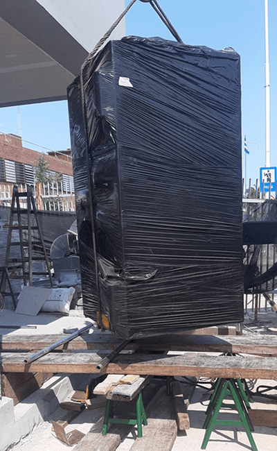 Una gran caja negra envuelta en plástico se encuentra encima de una paleta de madera.